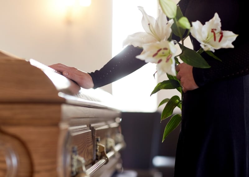 person holding flowers next to a casket